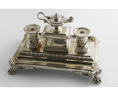 A VICTORIAN INKSTAND on a shaped rectangular base with foliate paw feet, tongue &amp; dart borders and two pen depressions, f