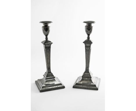 A PAIR OF GEORGE III CANDLESTICKS on bevelled square bases with tapering fluted columns, vase-shaped capitals and bead border