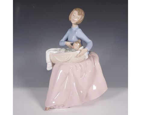 This Nao by Lladro porcelain figurine, titled Bundle of Love (model 1214), depicts a serene mother tenderly cradling her slee