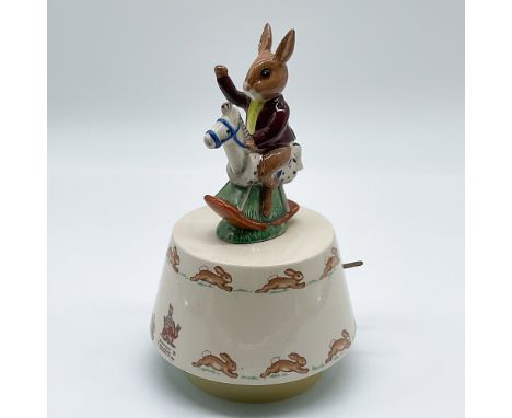 This Royal Doulton music box features a delightful design, depicting an adorable rabbit riding a rocking horse, beautifully h