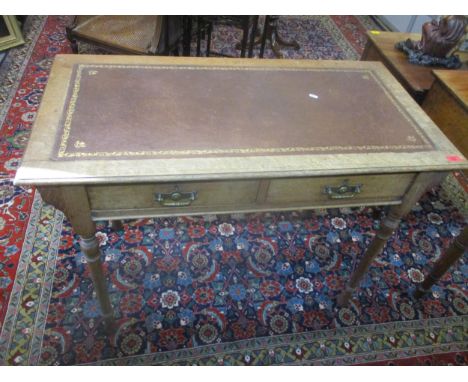 A late Victorian light oak two drawer writing desk with gilt tooled leather scriber, two frieze drawers with brass swan neck 