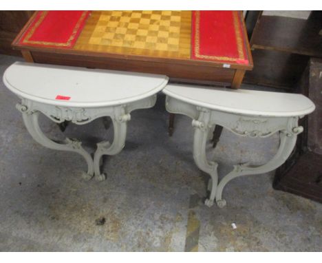 A pair of vintage painted wall hanging demi lune shelves having scroll carved decoration and single inset drawers, 48cm h x 5