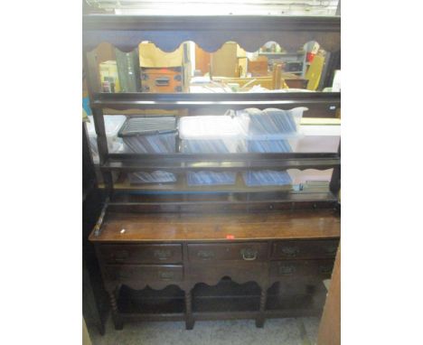 A 19th century oak dresser having a plate rack with faux drawers above five short drawers with bobbin turned supports and an 