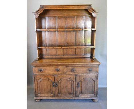 An Oak Dresser, the boarded shelf back above two drawers and three moulded doors, raised upon low bun feet, 138 cms wide, 45 