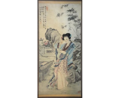 Chinese scroll painting depicting a lady seated on a rock in a garden, with calligraphy and two red seal marks, framed, 132cm