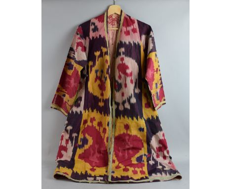 Two  chapan robes of woven ikat silk in purple, yellow, red and cream with typical boteh and geometric patterns. One with mac