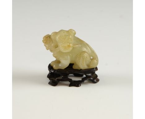 Chinese pale celadon and brown mottled jade lion with a plant in it's mouth, on carved hardwood stand, 5cm wide,.  