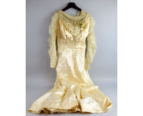  An Edwardian cream silk satin wedding dress  decorated with looped beadwork and an orange blossom and heather posy, together