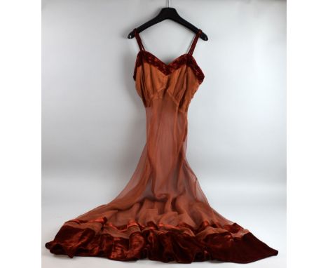 A 1930's rust chiffon evening dress with velvet trim, together with a peach satin long slip of the same era .  Both items in 