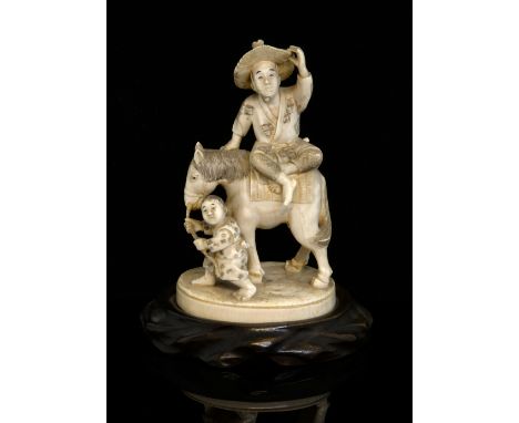 Late 19th/early 20th century Japanese carved ivory okimono of a man on a horse being led by a young boy, inset red signature 