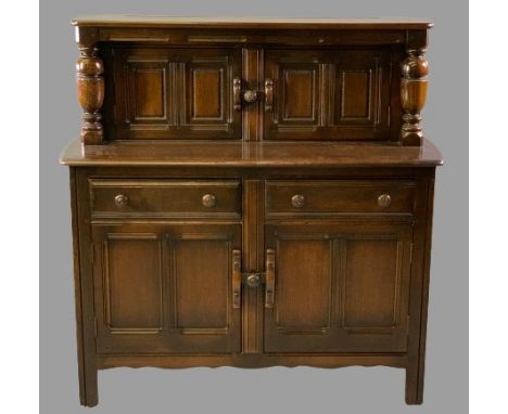 ERCOL OAK BUFFET SIDEBOARD with twin upper cupboard doors and bulbous top support detail over a base section of two drawers a