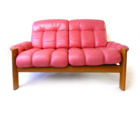 A 1970's teak two-seater sofa of organic form with fuchsia pink leather upholstery, l. 146 cm CONDITION REPORT: Normal wear t