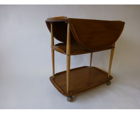 An Ercol elm drop-leaf trolley, the three tiers joined by beech supports  