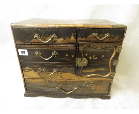 A late 19th/early 20th century Japanese lacquered table cabinet, gilded brass carrying and drawer handles, four short drawers