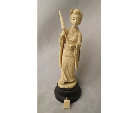 A late 19th century/early 20th century Japanese ivory Okimono figurine of a woman holding a closed parasol and a lantern, wit