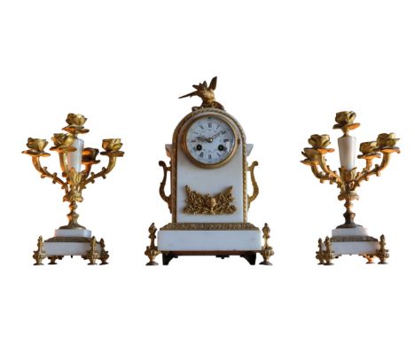 WHITE MARBLE AND GILT METAL GARINTURE DU CHEMINEE Louis XV style, the dome-shaped clock mounted by a bird finial, the white e