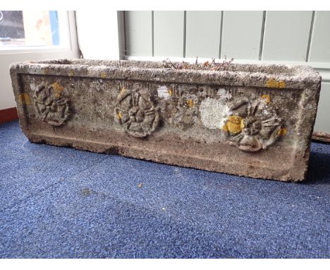 A WEATHERED RECONSTITUTED STONE GARDEN PLANTER of trough form cast with Tudor roses, with lichen growth 61 cm wide
