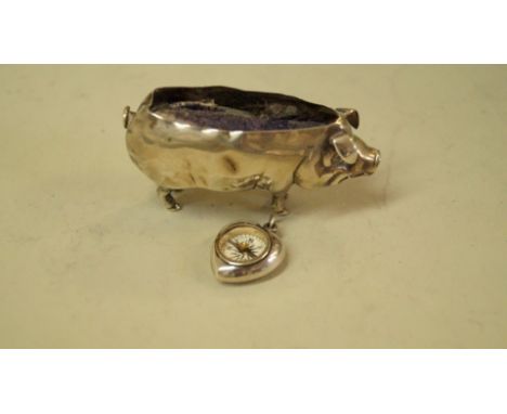 An Edwardian silver novelty pig pin cushion, by Adie & Lovekin Ltd, Birmingham 1905, 6.5cm; and a silver heart shaped compass