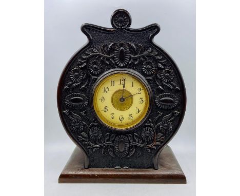An enamel faced circular carved mantel clock.