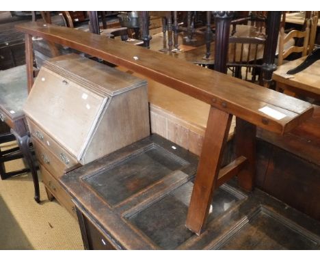 A cherry wood bench, the single plank top raised upon trestle supports