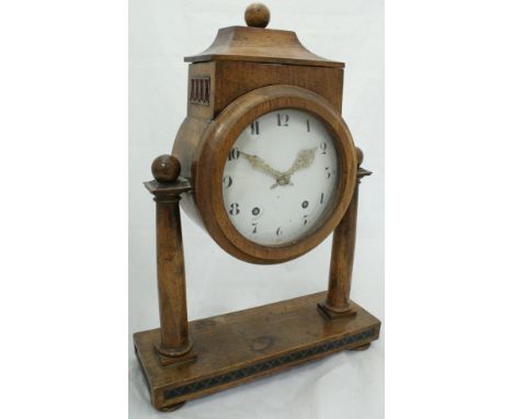 An walnut cased mantle clock with 8-day movement raised upon twin columns and with Arabic numerals to the circular enamelled 