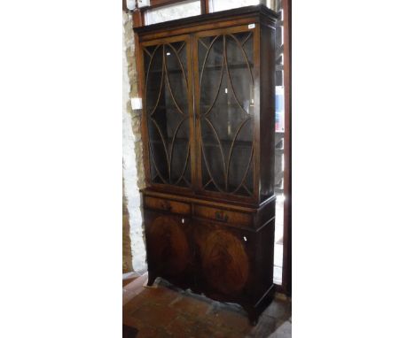 A mahogany and banded bookcase cabinet with Greek key moulded cornice above the two astragal glazed doors enclosing shelves a