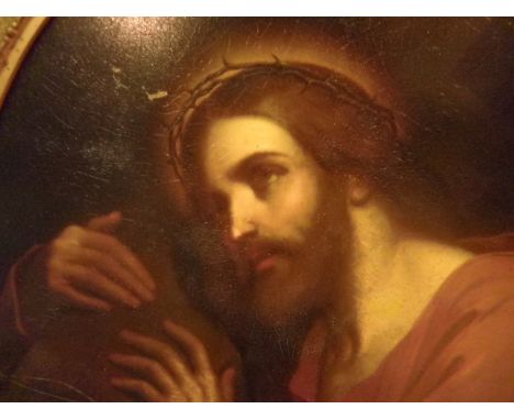 An oval portrait of Jesus holding the cross, oil on board (40cm x 32cm) in a gilt frame.