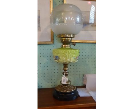 A late 19th/early 20th century oil lamp, the circular globe over green glass hand painted reservoir on gilt column (54cm).