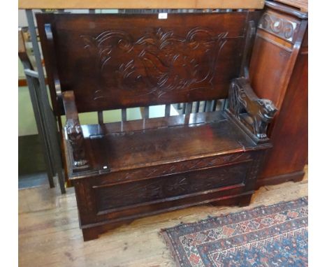 An oak monk's bench, having carved decoration and stylized lion arms (107cm).