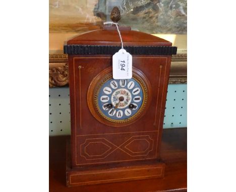 An Edwardian and mahogany inlaid mantel clock, curved top surmounted by pineapple finial, the enamel dial with Roman numerals