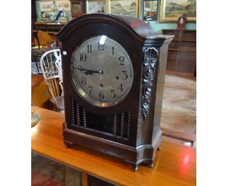 An early 20th century oak cased round top mantel clock, having carved decoration, the silvered dial bearing Arabic numerals (