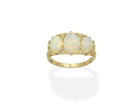 An opal and diamond ringThe trio of oval opal cabochons with rose-cut diamond accents, between foliate shoulders, one opal ch