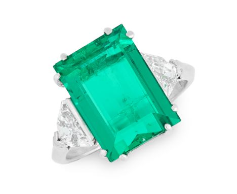 A COLOMBIAN EMERALD AND DIAMOND RING in platinum, set with a step cut emerald of 7.19 carats, between fancy cut diamond set s