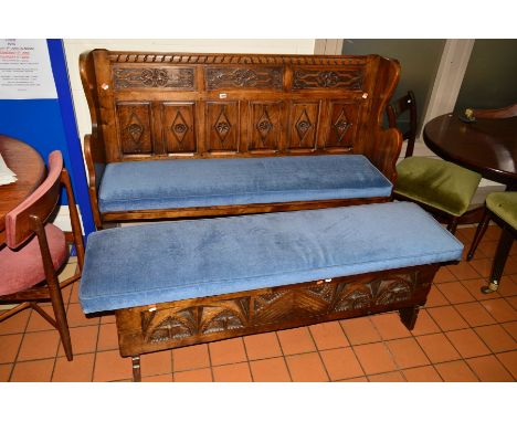 A REPRODUCTION CARVED OAK HALL SETTLE, having various carved panels with a blue upholstered seat, width 153.5cm x depth 49cm 