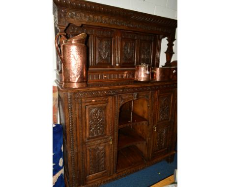 A LATE 19TH CENTURY CARVED OAK PRESS CUPBOARD/SIDEBOARD, incorporating older timbers, overhanging top. The top flanked by squ