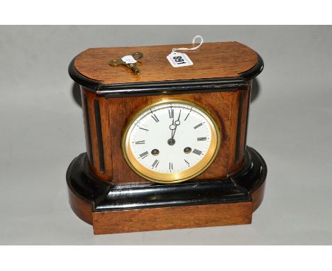 A LATE VICTORIAN WALNUT AND EBONISED MANTEL CLOCK, the shaped rectangular case with rounded ends and fluted sides, enamel dia