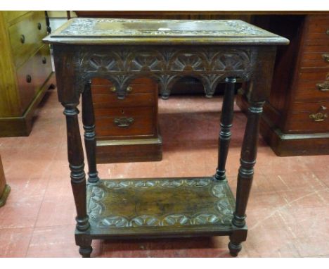 A CARVED OCCASIONAL TABLE, two tier with carved fruit border and carved lunettes to the base shelf, on turned corner supports