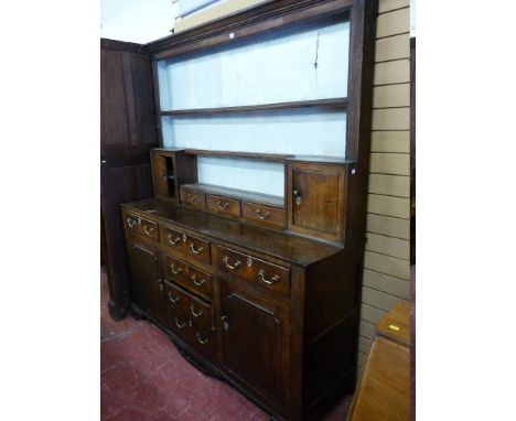 AN EARLY 19th CENTURY OAK WELSH DRESSER, the rack having reeded end columns to a small cupboard at each end with three shelve