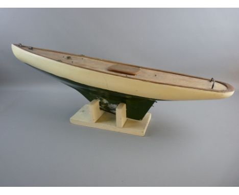A VINTAGE POND YACHT HULL on stand, clinker built with green and white livery and lead keel (no mast or sails)