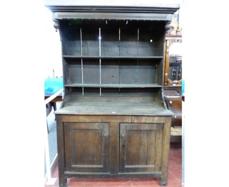 AN EARLY 18th CENTURY SIMPLE OAK WELSH DRESSER with twin shelf rack having a deep hood to a base of two cupboards, 128 cms wi