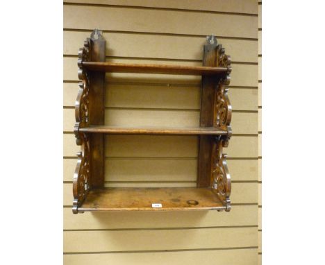 AN OAK THREE SHELF WALL RACK, the graduating shelves with decorative scroll fretwork sides and mounting brackets, 67 x 51.5 c