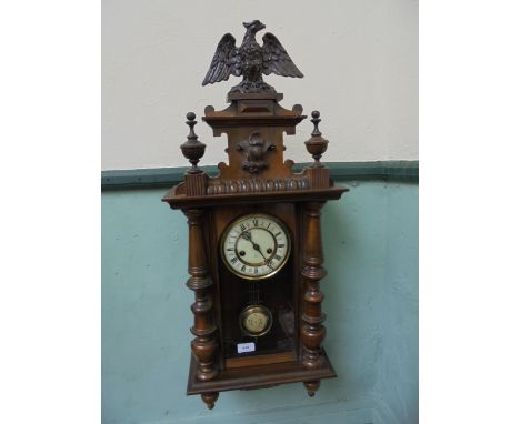 Oak cased late Victorian wall clock with eagle mount to top, circular brass and enamel dial inset roman numerals, brass pendu