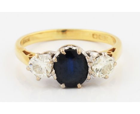 An 18ct yellow gold sapphire and diamond three stone ring, set with a central oval cut sapphire, measuring approx. 6x5mm, wit