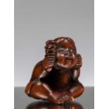 NETSUKE OF A SEATED CHILD WITH RATTLE