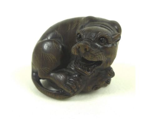 A Japanese netsuke in the form of a tiger playing with her cub, the carved wooden body inset with mother of pearl button to b