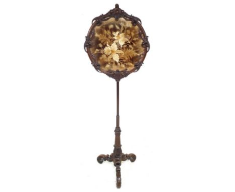 A late Victorian rosewood firescreen, with foliate carved oval frame, on a turned column with three C scroll carved legs, 57 