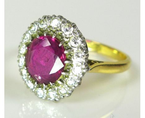 An 18ct gold, platinum, diamond and ruby ring, the oval ruby of approximately 8.2 by 7.1mm and surrounded by sixteen diamonds