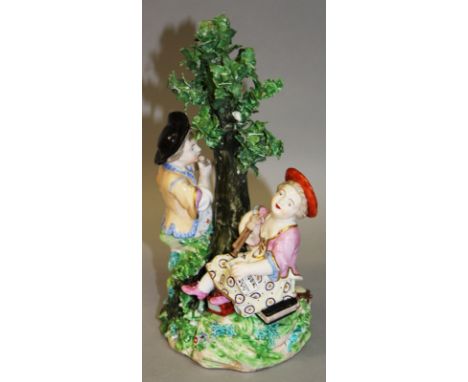 AN 18TH CENTURY DERBY FINE GROUP OF A BOY AND GIRL playing the flute and bagpipe, seated on a rocky mound beside a tree, mode