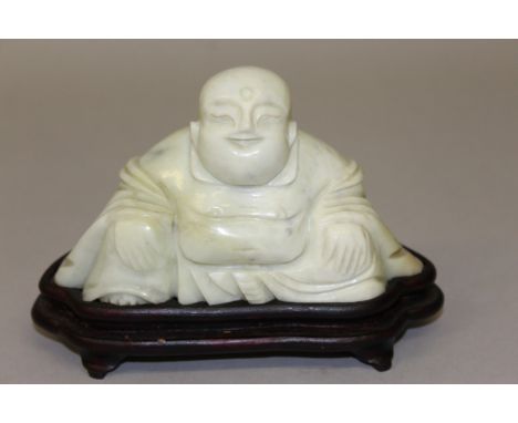 A JADE BUDDHA on a wooden stand. 6ins wide. 
