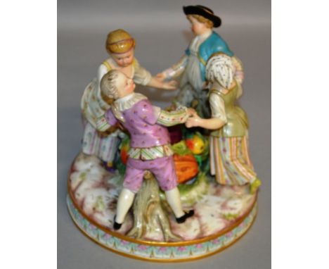A GOOD MEISSEN GROUP OF FOUR CHILDREN DANCING playing Ring A Ring O’ Roses around a large basket of fruit, on a circular base